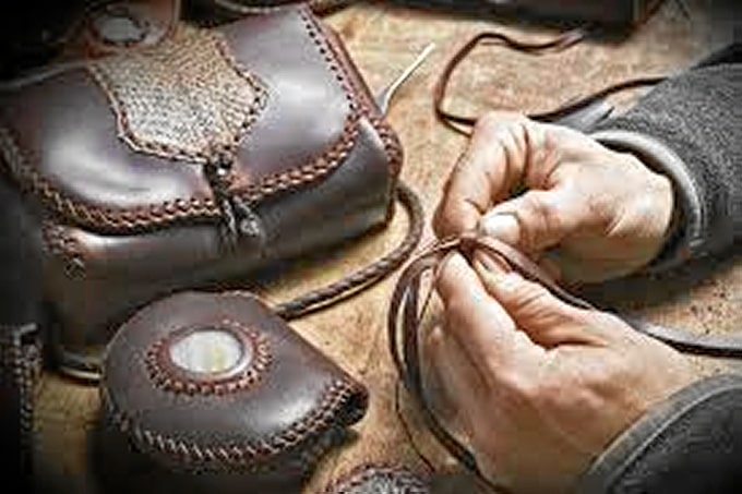 Artesanía del cuero. Artesano trabajando el cuero con la smanos y herramientas sencillas.